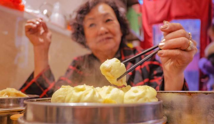 Người phụ nữ châu Á lớn tuổi ăn bánh bao nhỏ trong nhà hàng Trung Quốc