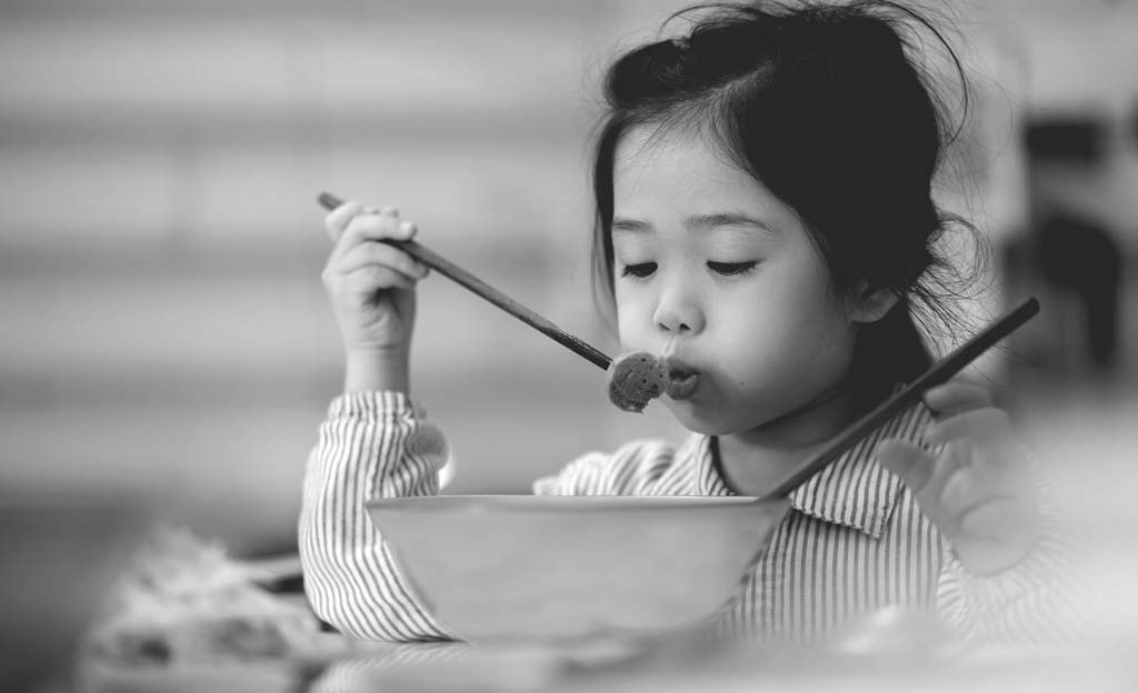 Cô bé ăn bằng đũa từ bát