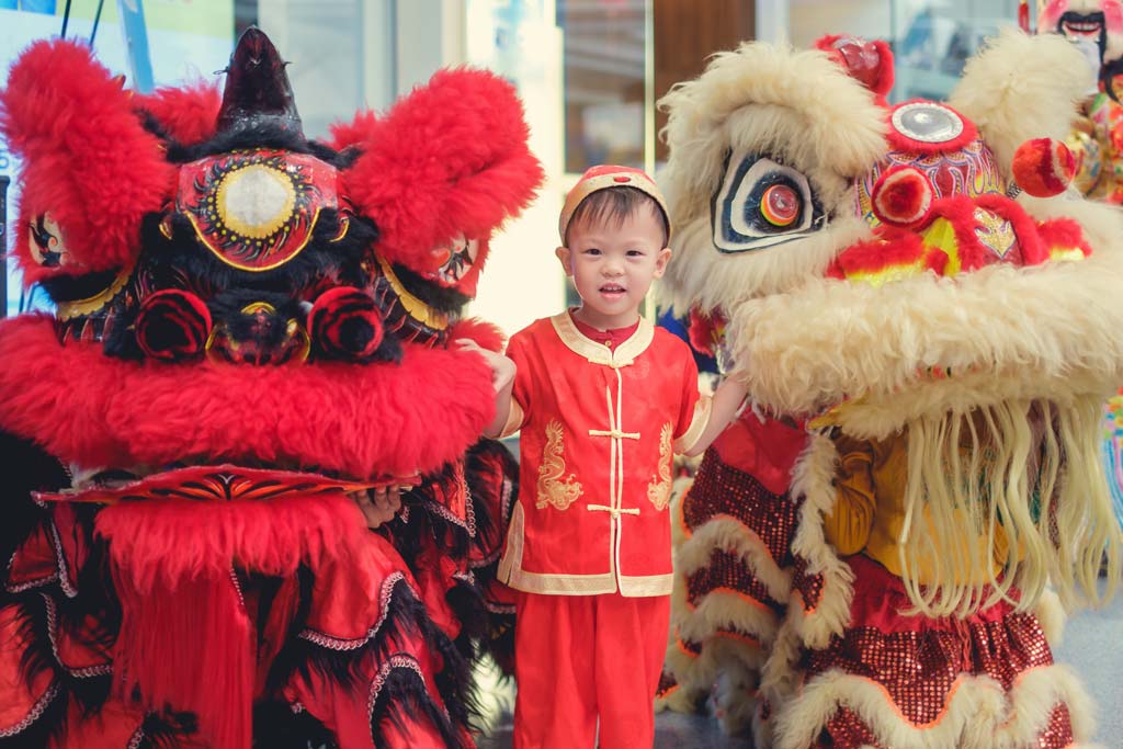 Cậu bé trong Đồ truyền thống màu đỏ của Trung Quốc đón Tết Nguyên đán với màn múa lân Trung Quốc