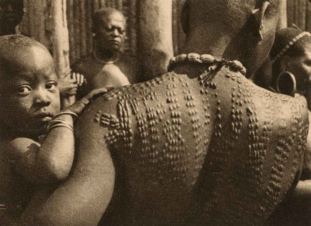 Người phụ nữ Bamum với vết sẹo trên lưng có hoa văn bế con
