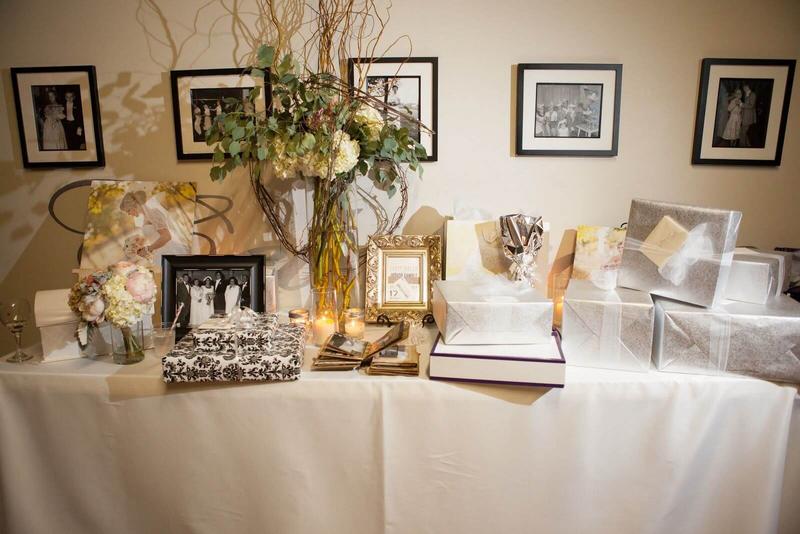 ý tưởng trang trí tiệc cưới  - Bàn gallery tối giản sẽ bao gồm những phụ kiện trang trí như nến trắng, lọ hoa, lá cây, khăn trải bàn trắng và ảnh chụp của cô dâu chú rể