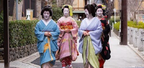 Geisha (tiền cảnh) và maiko (nền) trên đường phố Kyoto.